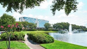 A park with a fountain, a pathway, and a building in the background. - Renaissance Orlando Airport Hotel by Marriott (Orlando)