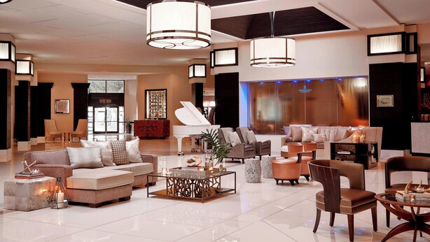 A spacious living area with a grand piano, comfortable seating, and modern decor. - Renaissance Orlando Airport Hotel by Marriott (Orlando)