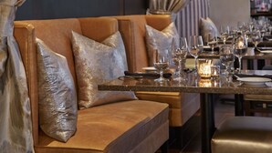 A dining area with a sofa and table set for a meal, featuring a candle centerpiece. - Renaissance Orlando Airport Hotel by Marriott (Orlando)