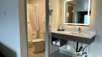 A bathroom with a white sink, mirror, and toilet.