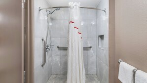 A shower area with a white shower curtain, a handheld showerhead, and a grab bar. - Red Roof Inn Chicago - Joliet (Joliet)