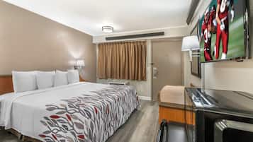 Une chambre d’hôtel avec un lit, un bureau, une télévision et une porte.
