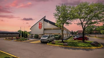 A Red Roof Inn with a parking lot, a van, and a red car parked outside.