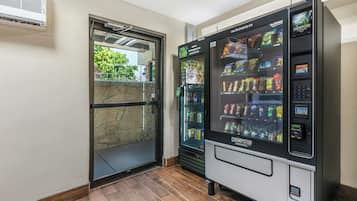 Un distributeur automatique de collations et une fontaine à eau, une entrée avec une porte en verre et un mur en pierre.