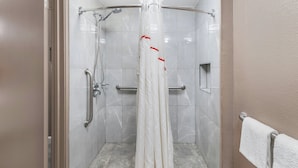 A shower area with a white shower curtain, a handheld showerhead, and a grab bar.