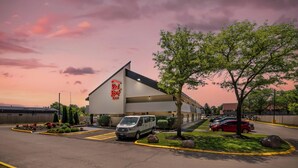 A Red Roof Inn with a parking lot, a van, and a red car parked outside.