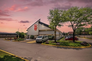 A Red Roof Inn with a parking lot, a van, and a red car parked outside.