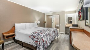 A hotel room with a bed, bedside table, chair, desk, and mirror. - Red Roof Inn Chicago - Joliet (Joliet)