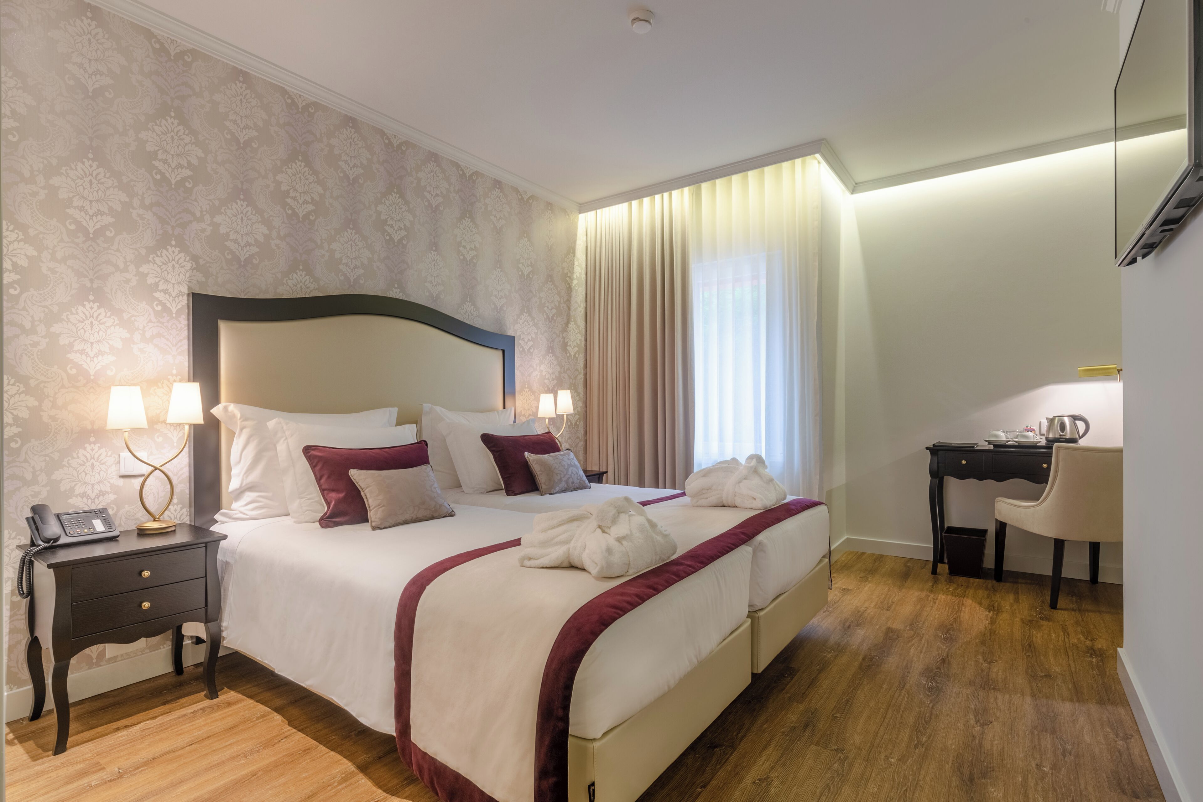 A hotel room with a large bed, bedside lamps, a desk, and a chair.