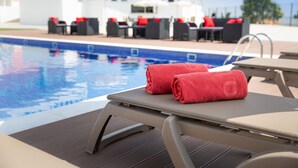 A poolside area with lounge chairs and a table, a pool, and outdoor seating with umbrellas. - Luna Hotel Turismo (Abrantes)
