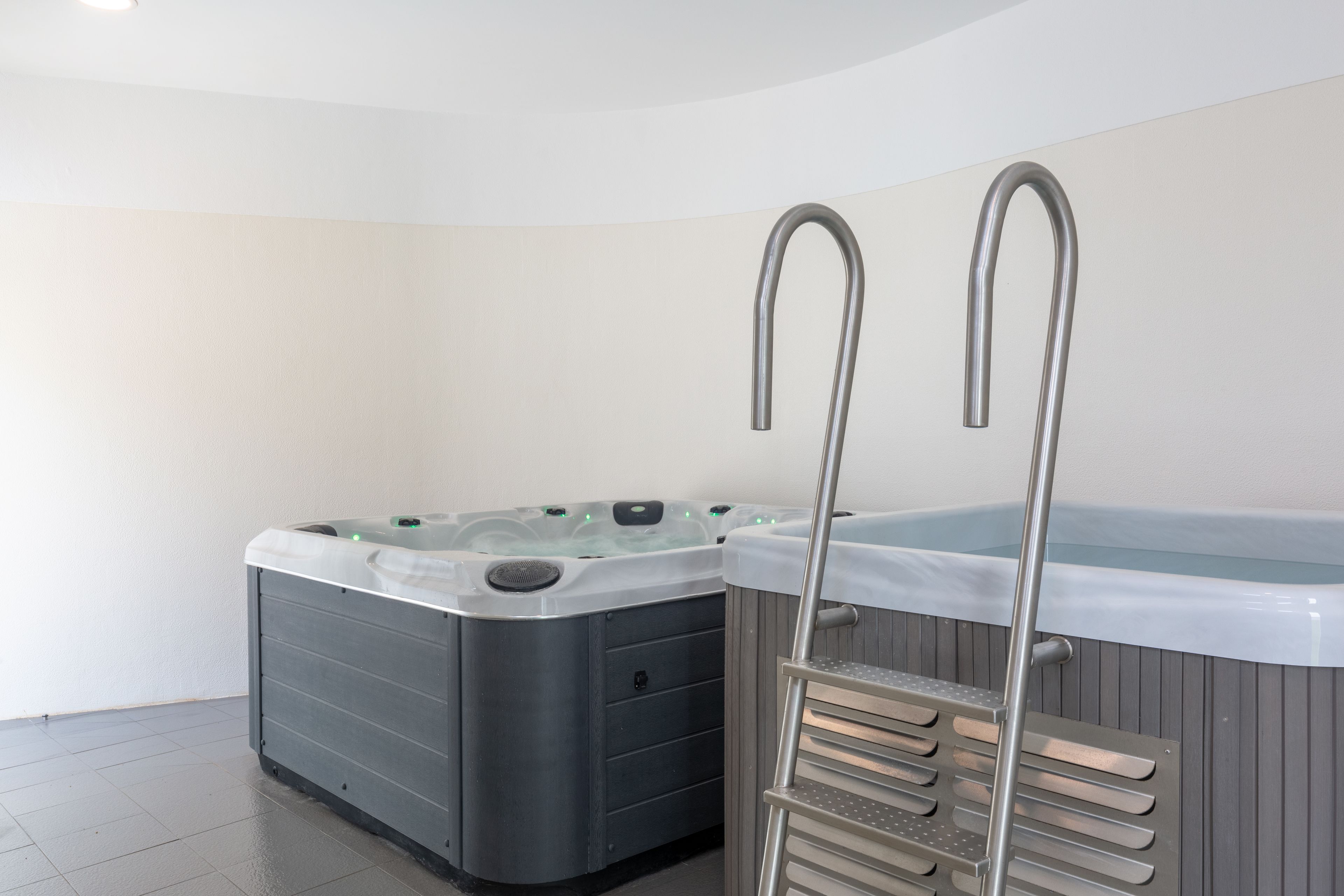 Ett spaområde med två bubbelpooler och en metallstege.