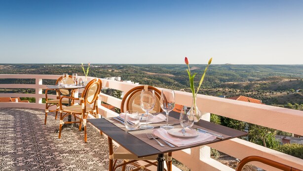 A dining table set with chairs and a view of the countryside. - Luna Hotel Turismo (Abrantes)