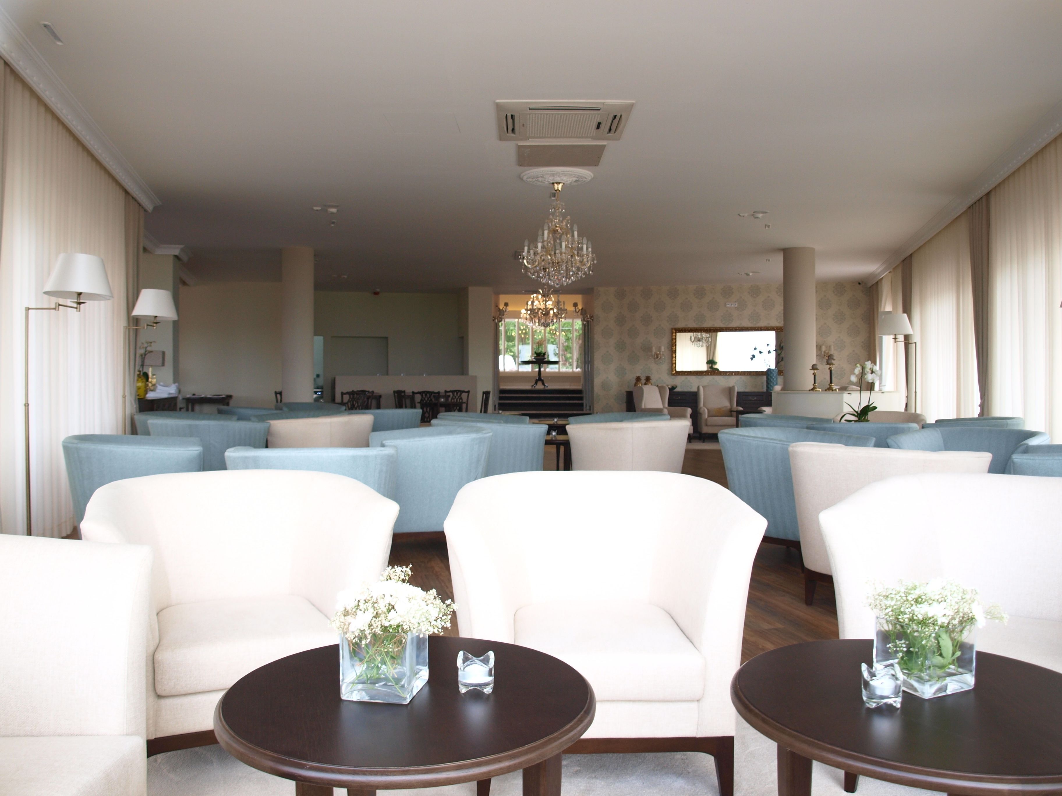 Een ruime hotellobby met zithoeken, een kroonluchter en uitzicht op het omliggende landschap.