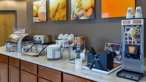 A breakfast bar with toasters, a coffee machine, and a syrup dispenser. - Comfort Inn Hammond I-94 (Hammond)