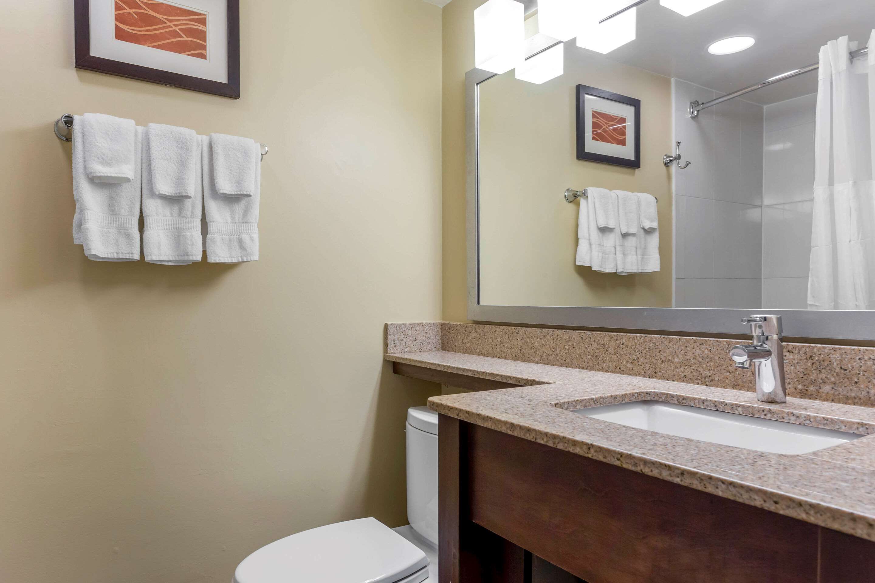 A bathroom with a sink, mirror, and two towels hanging on the wall.