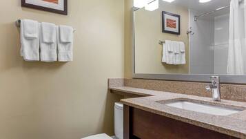 A bathroom with a sink, mirror, and two towels hanging on the wall.