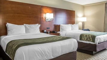 Habitación de hotel con dos camas, cabeceros de madera, lámparas de noche y un mostrador de recepción.