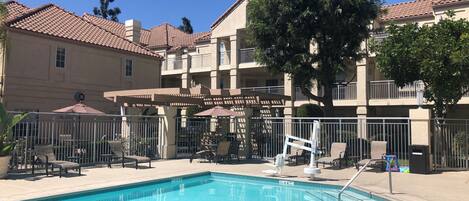 Una piscina al aire libre, sillones reclinables de piscina