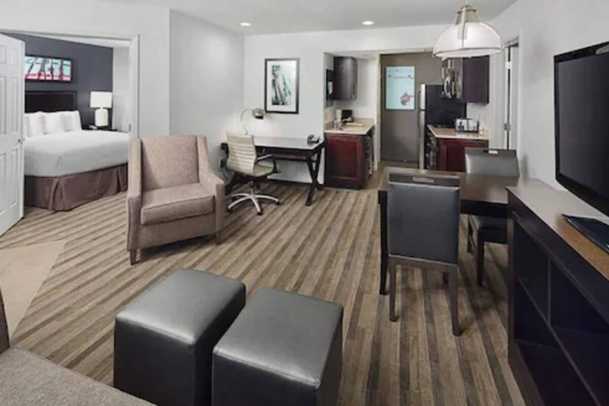 Une chambre d’hôtel équipée d’un lit, d’un bureau, d’une chaise, d’une télévision et d’une kitchenette.