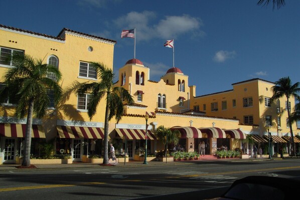 A yellow building with red awnings and palm trees in front. - Colony Hotel & Cabaña Club (Delray Beach)