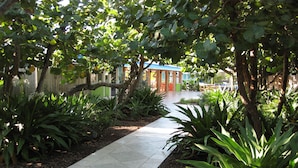 A pathway leading to a building with a green roof, surrounded by lush greenery and trees. - Colony Hotel & Cabaña Club (Delray Beach)