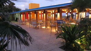 An outdoor dining area with tables and chairs, a covered seating area, and an American flag. - Colony Hotel & Cabaña Club (Delray Beach)