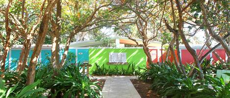 Un camino que lleva a un edificio con una pared verde y un letrero blanco.