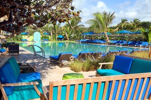 A poolside area with lounge chairs and umbrellas, surrounded by palm trees and a clear sky. - Colony Hotel & Cabaña Club (Delray Beach)