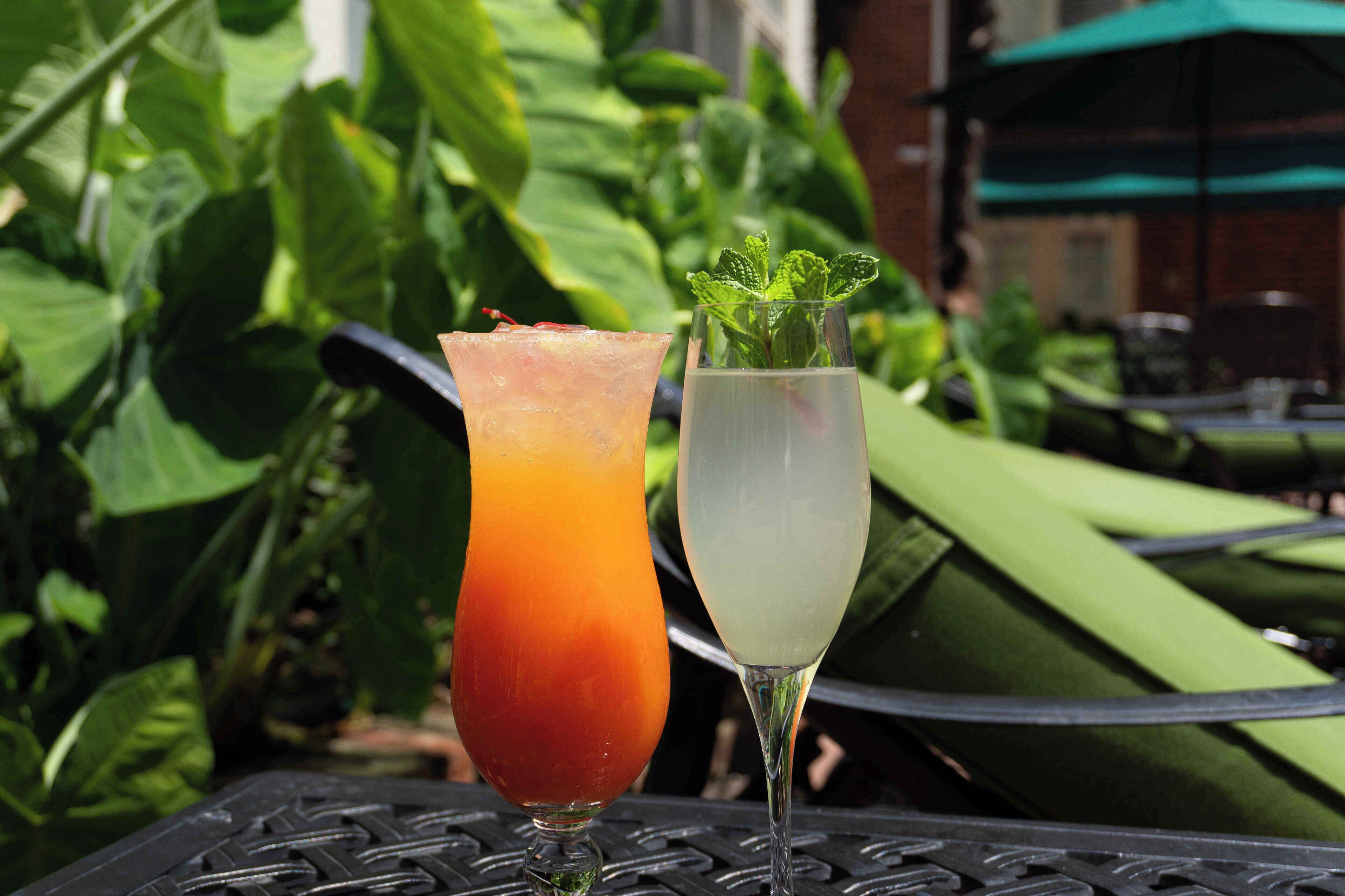 Deux boissons sur une table, avec un parasol vert en arrière-plan.