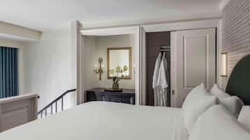 Habitación de hotel con una cama grande, un tocador, un espejo y una puerta que da a otra habitación.