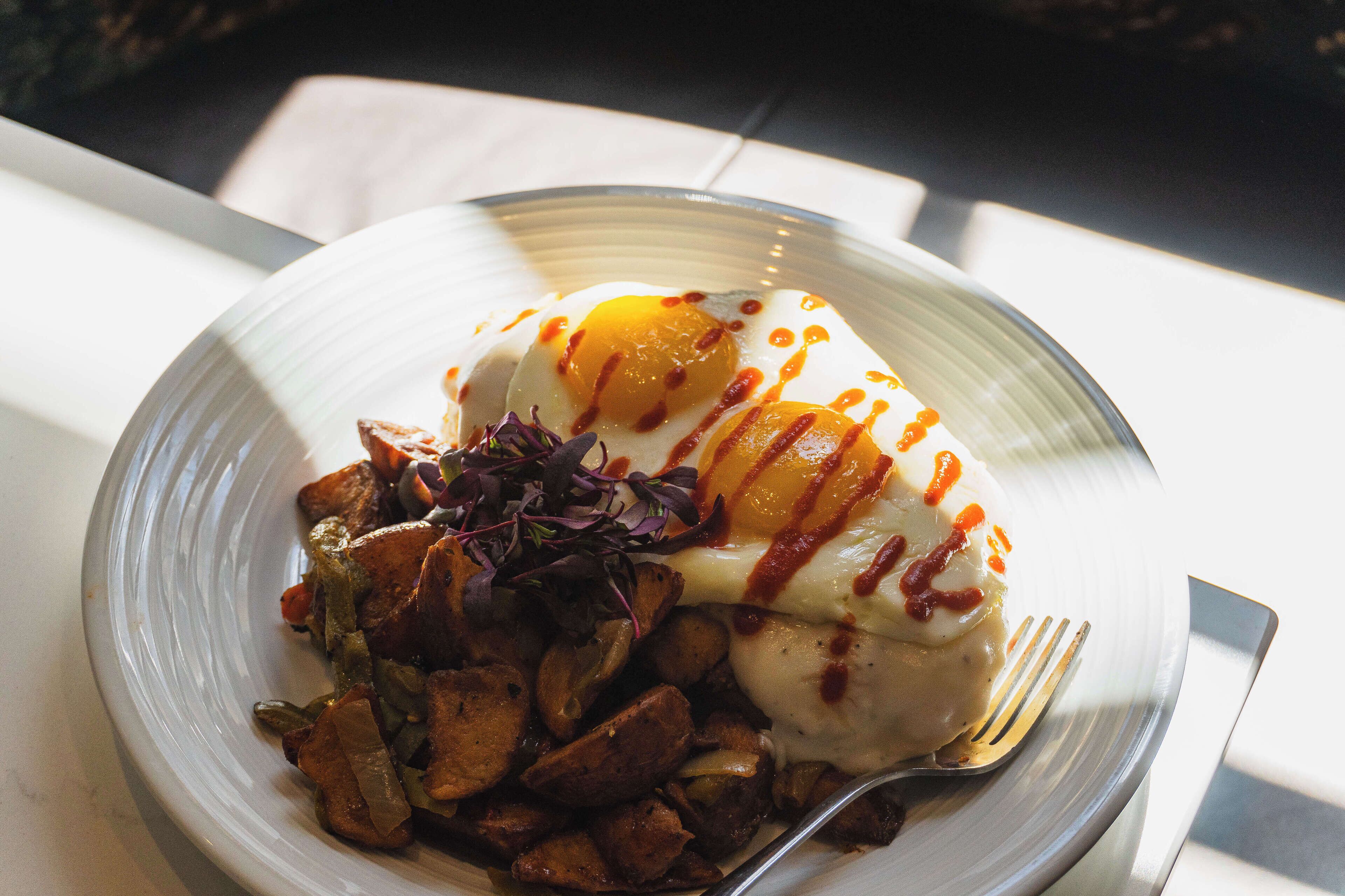 A plate with a poached egg, roasted potatoes, and a small salad.