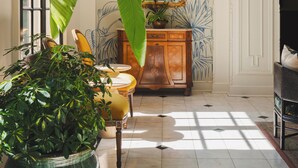A room with a large mirror, a potted plant, and a wall mural. - Bourbon Orleans Hotel (New Orleans)