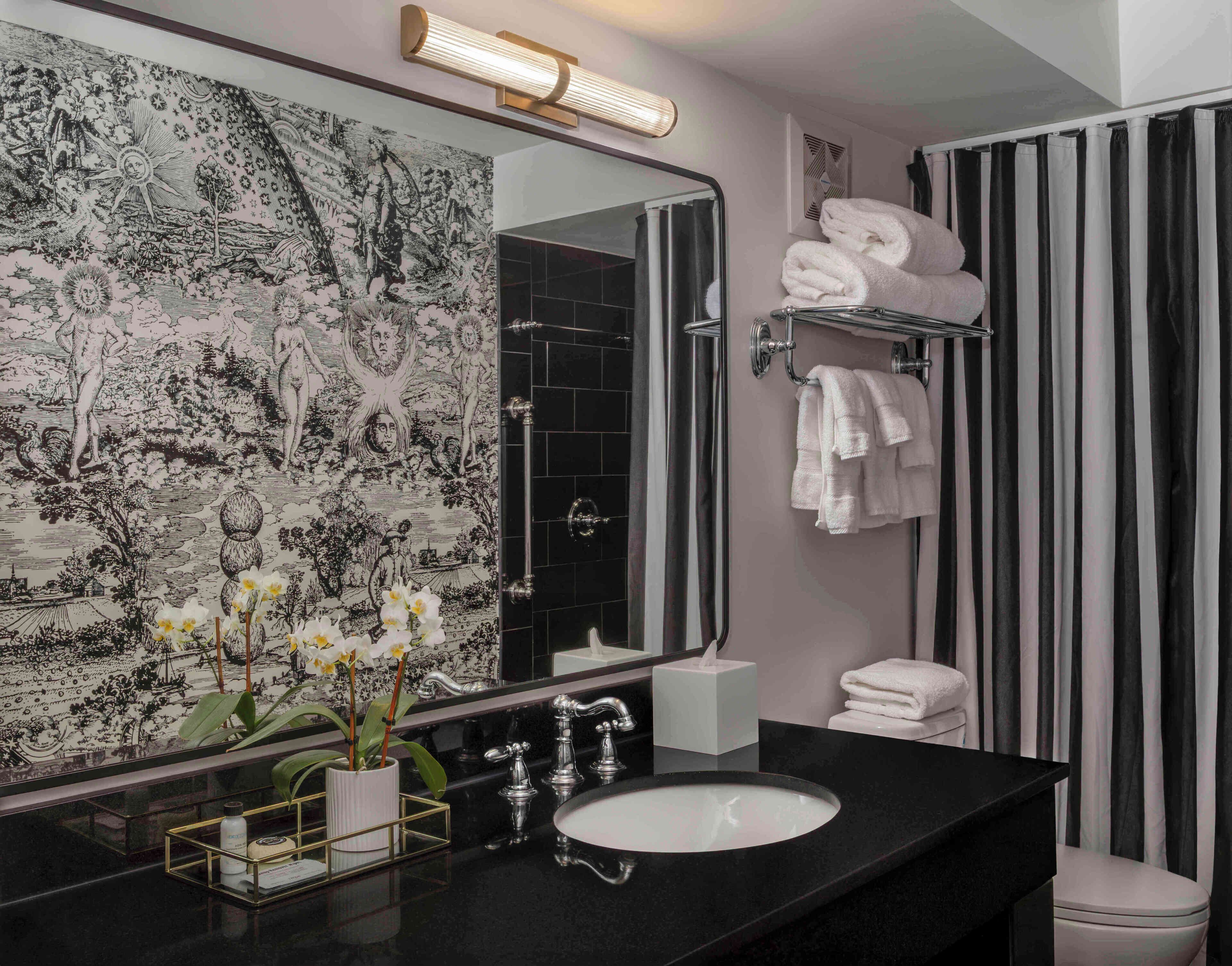 A bathroom with a black sink, a large mirror, a towel rack, and a shower curtain.
