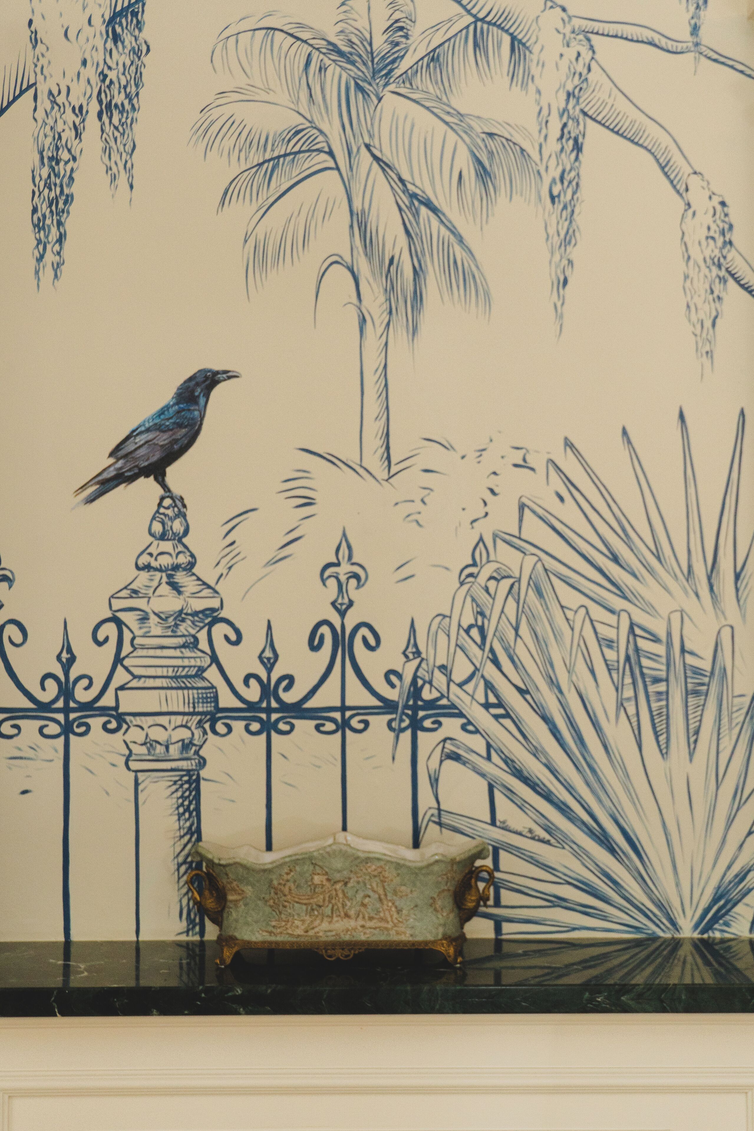 A wall with a bird perched on a decorative column, a bench, and a plant.
