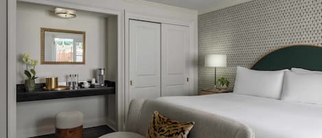 Une chambre d’hôtel avec un lit, un canapé, une petite table avec une lampe, un miroir et un mur décoré d’un motif.