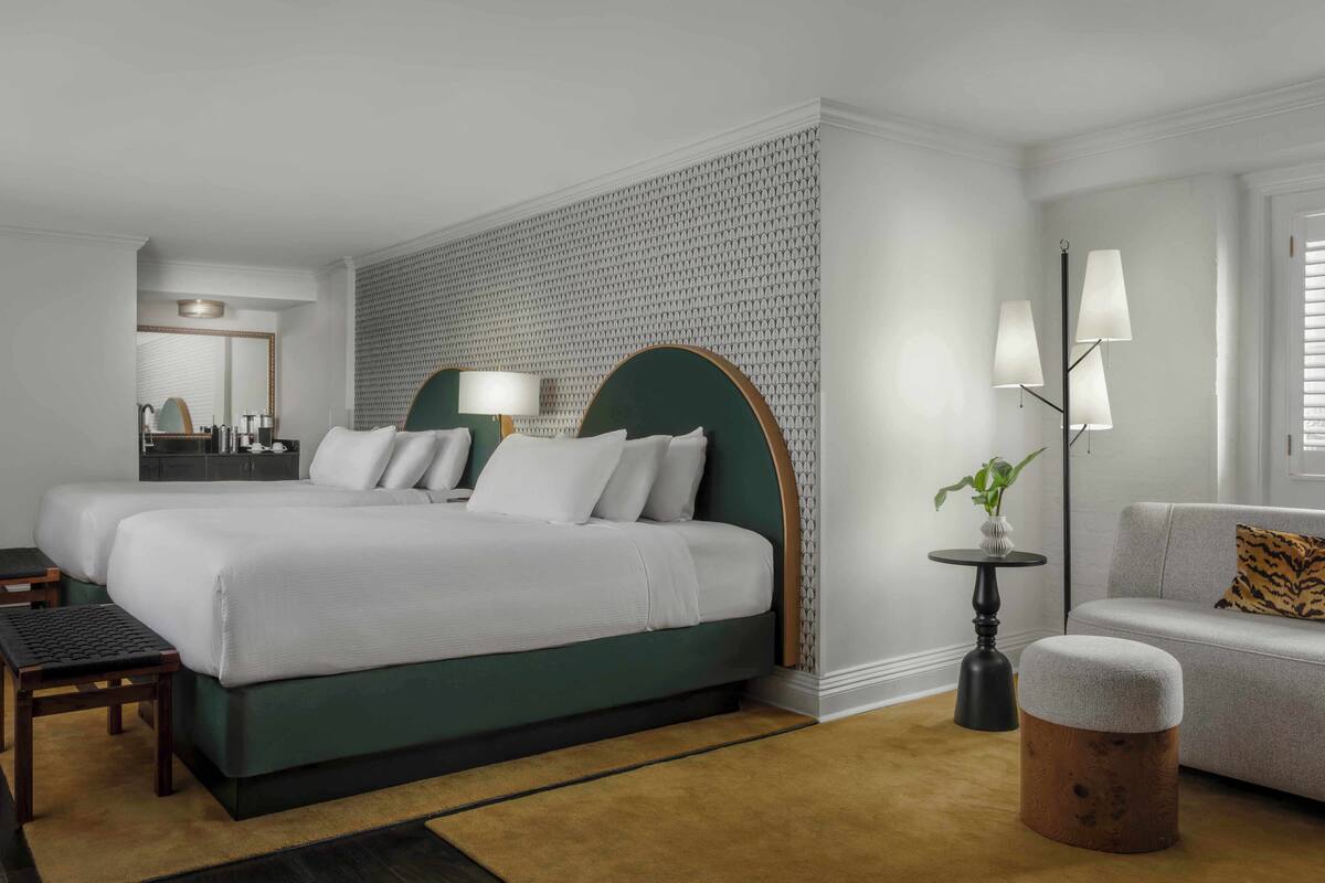 Een hotelkamer met twee bedden, een bank, een kleine tafel en een lamp.