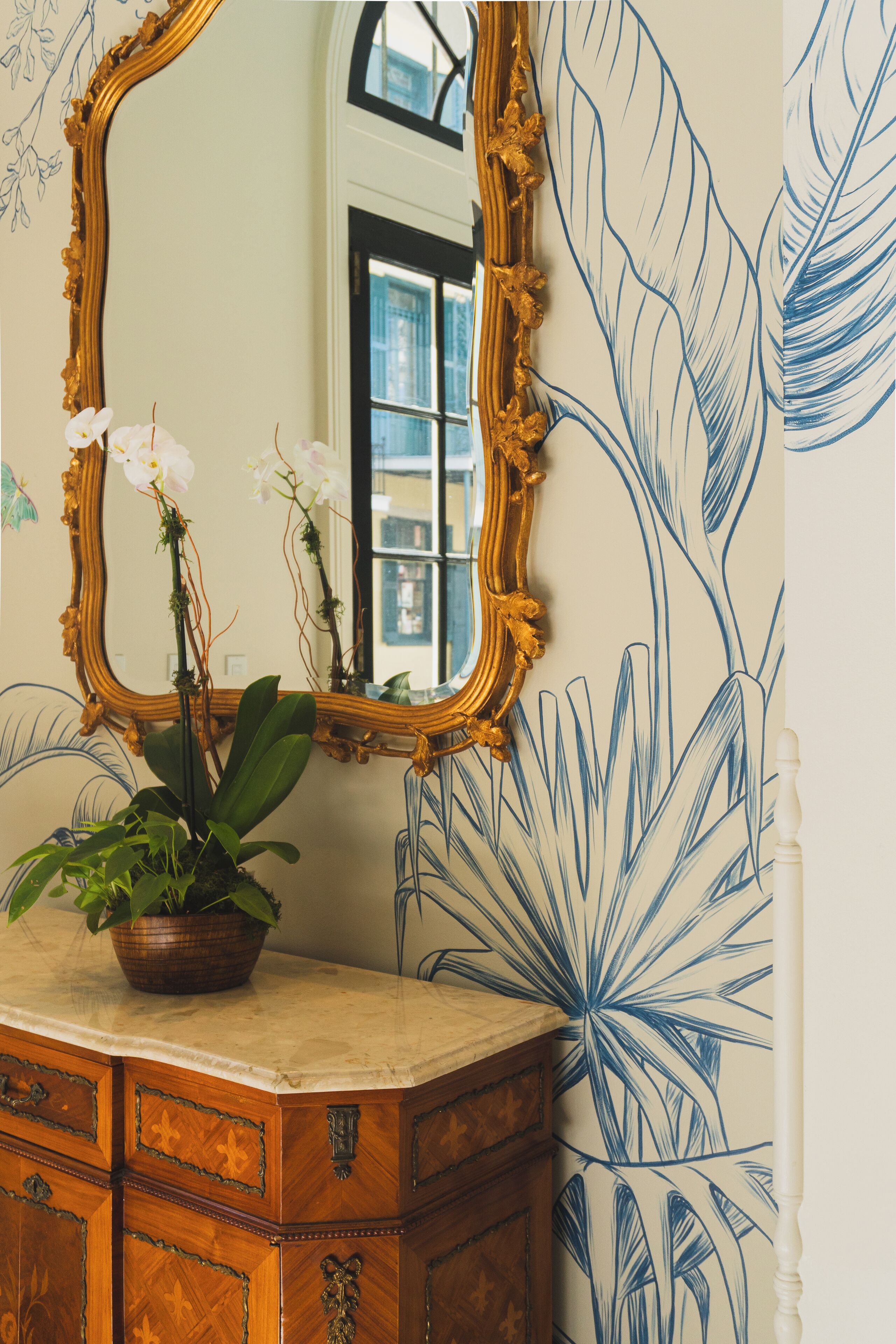 Ein Badezimmer mit einem großen Spiegel, einer Holzausstattung und einem Wanddesign mit Blumenmuster.