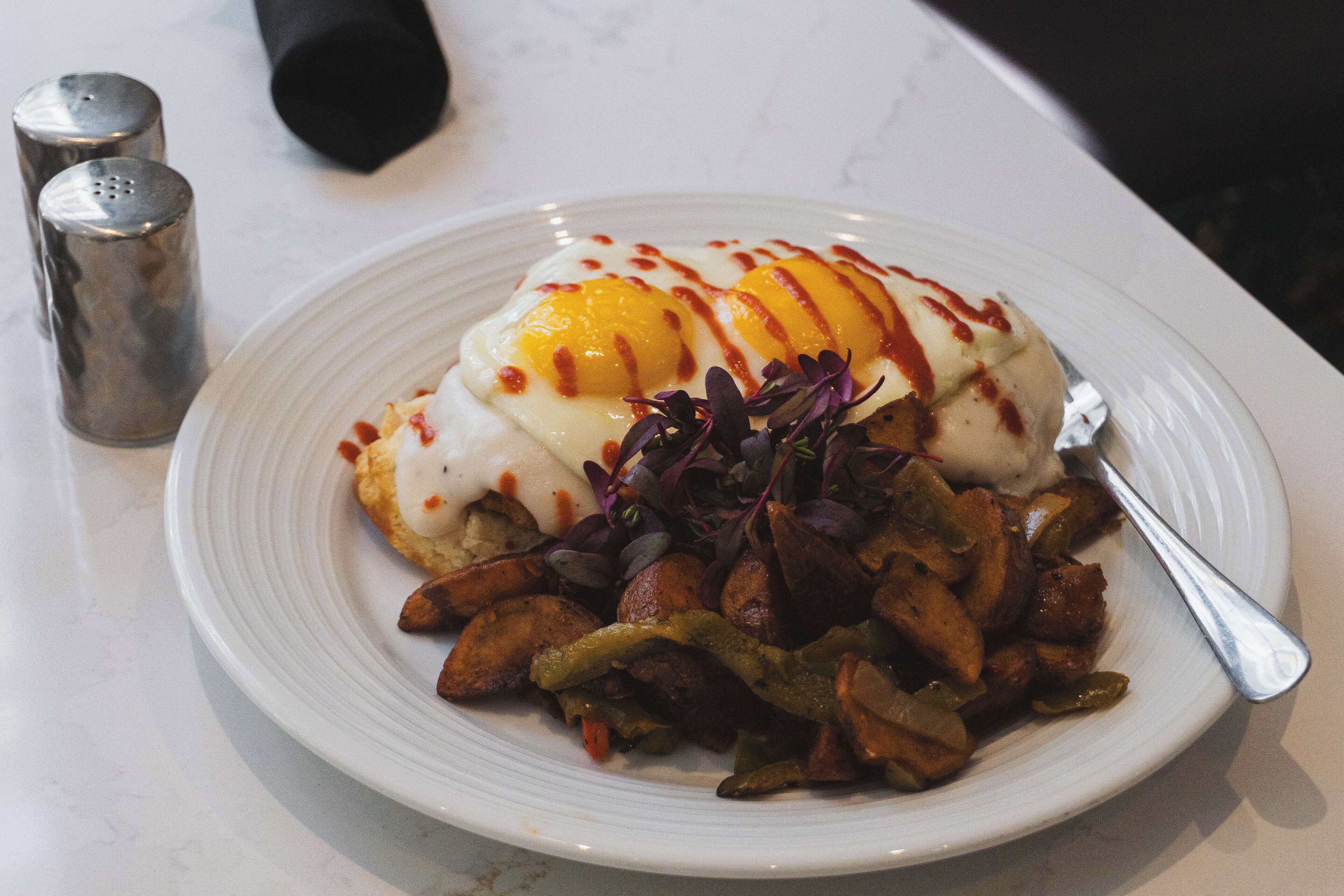 A plate of food with eggs, potatoes, and greens.