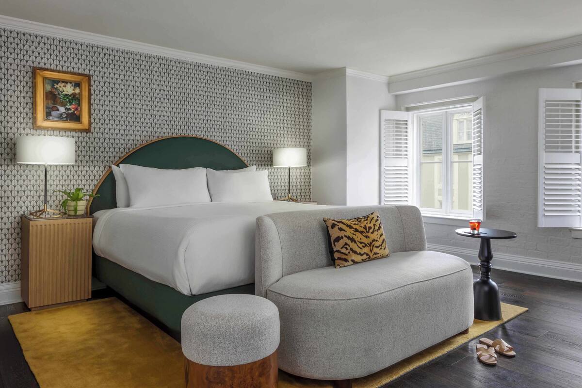 Een hotelkamer met een bed, een bank, een kleine tafel en een raam met shutters.