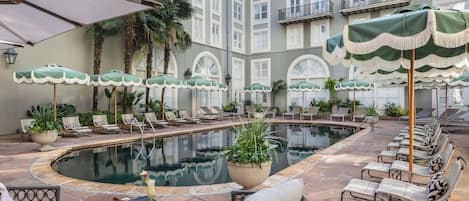 A poolside area with lounge chairs, umbrellas, and a pool.
