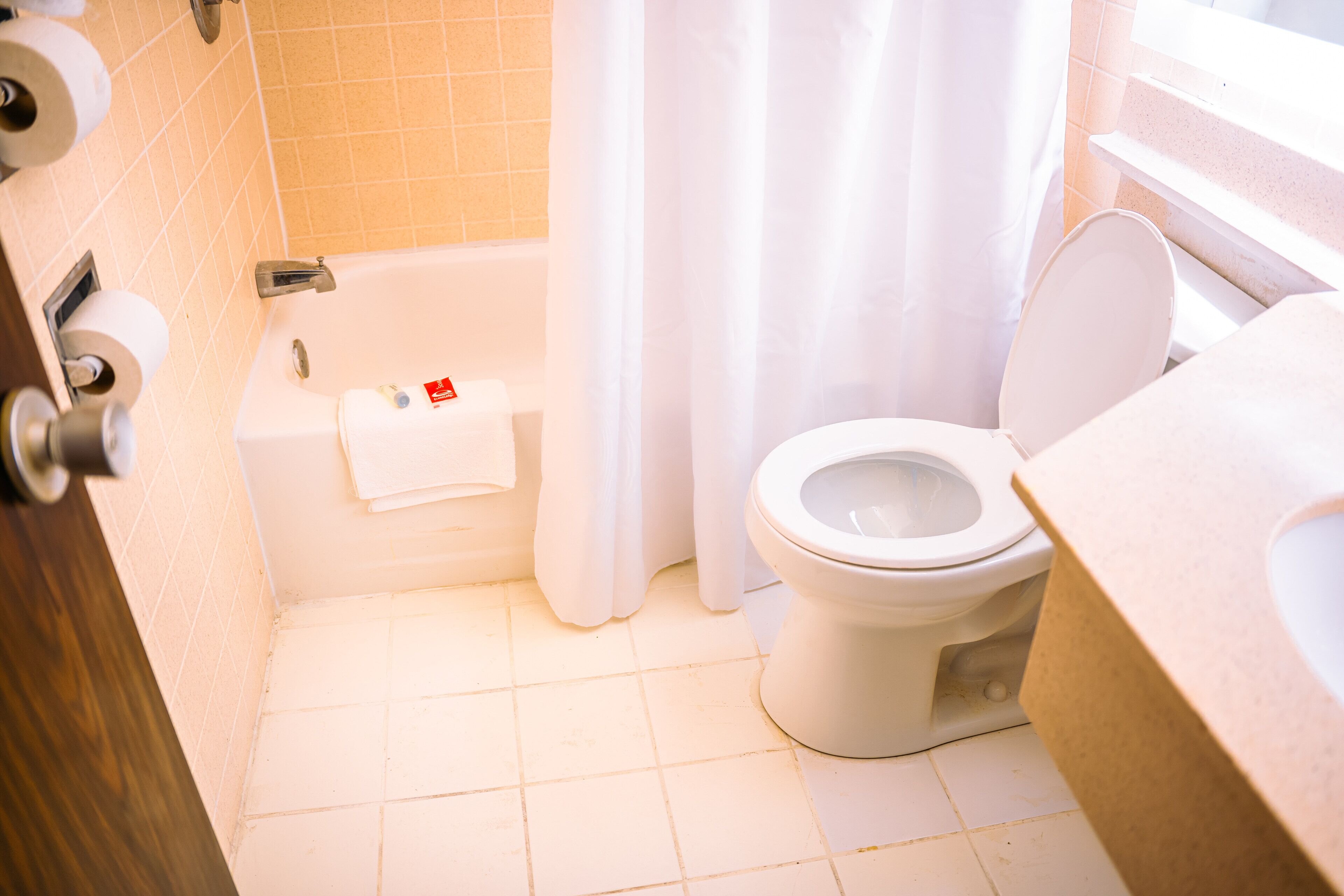 A bathroom with a toilet, a bathtub, and a shower curtain.