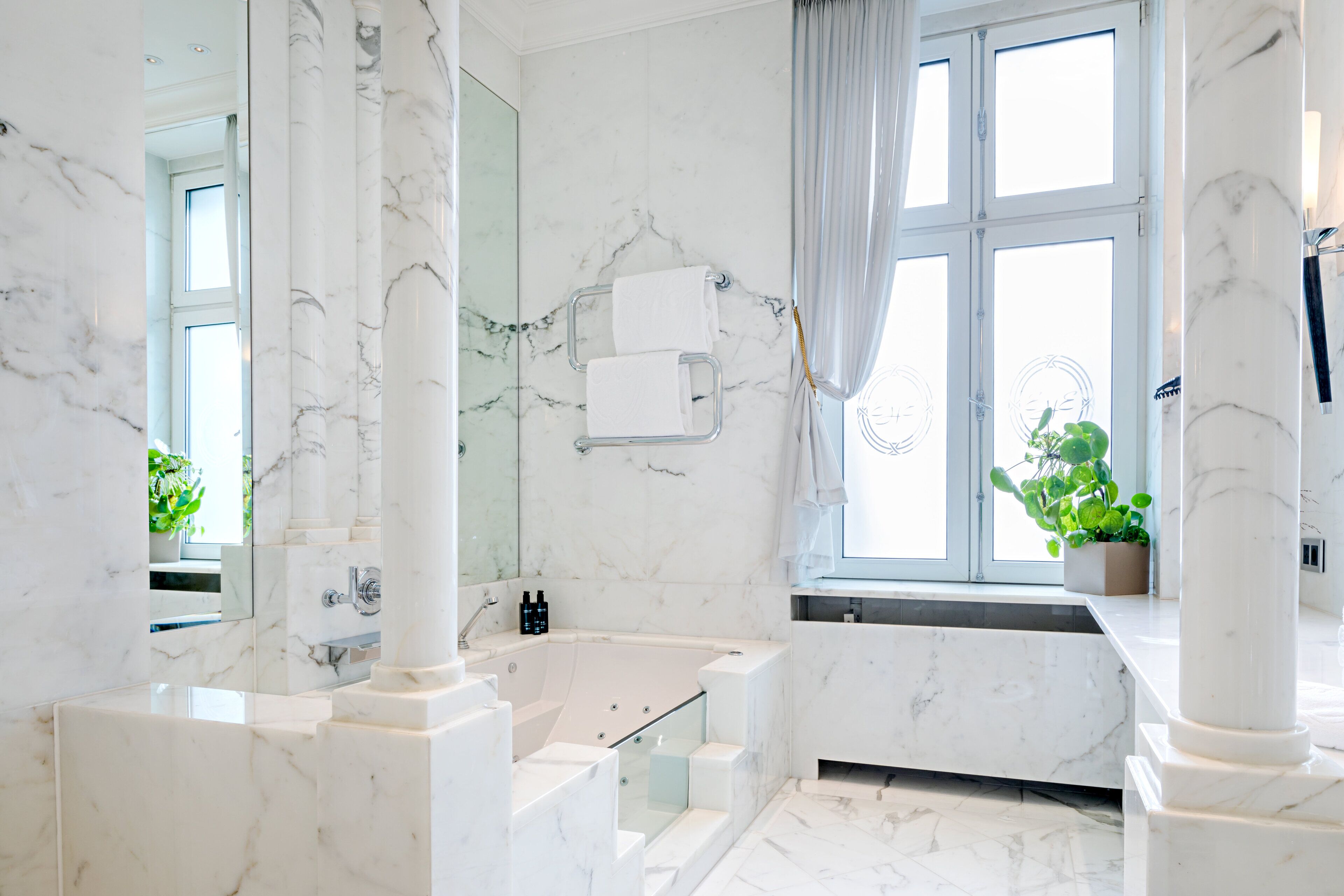 A modern bathroom with a marble floor, a bathtub, and a window with a view.