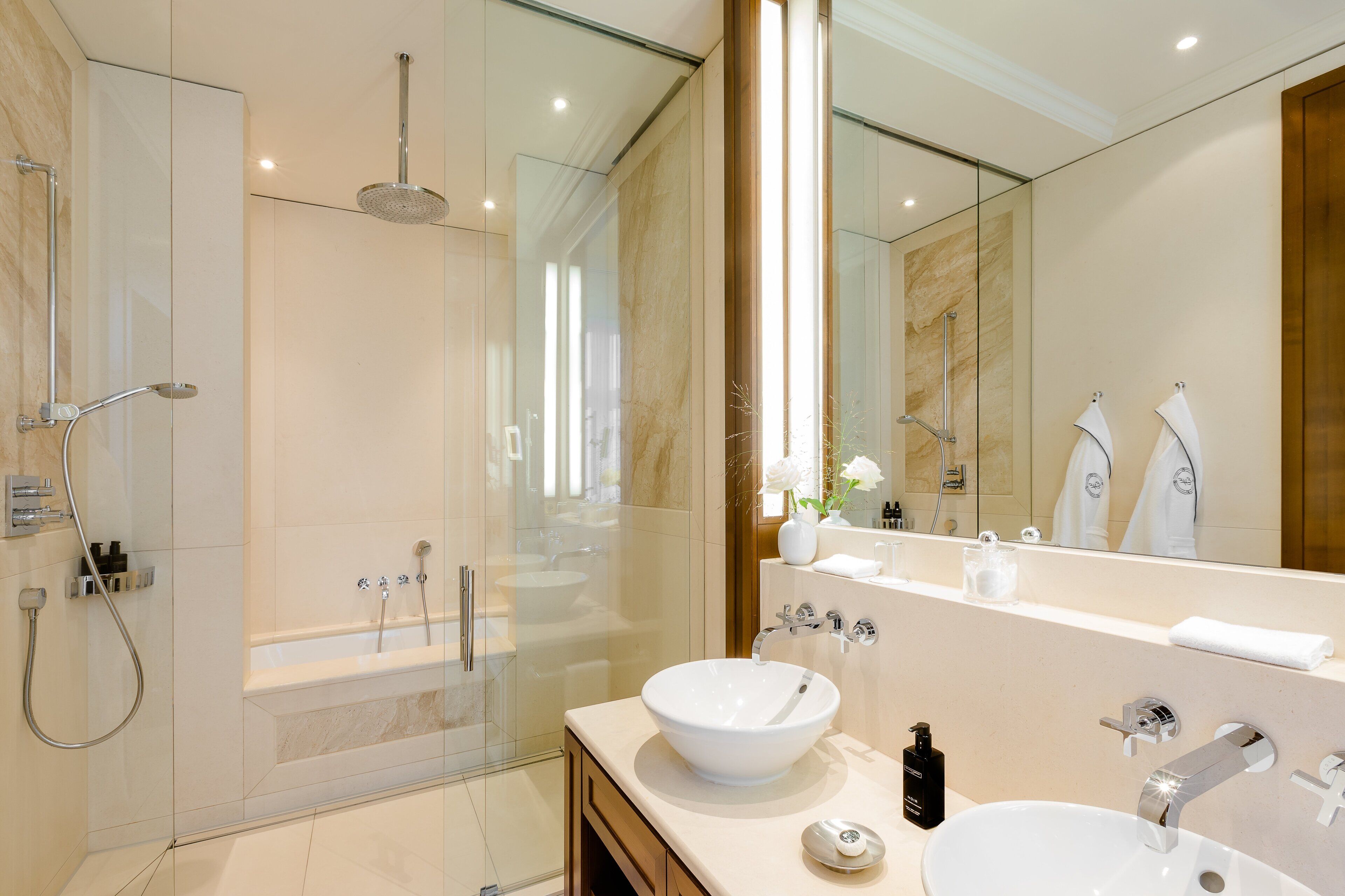 Un bagno moderno con doccia vetrata, uno specchio grande e un lavandino bianco.