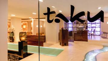 A modern hotel lobby with a reception desk, seating area, and a decorative water feature.