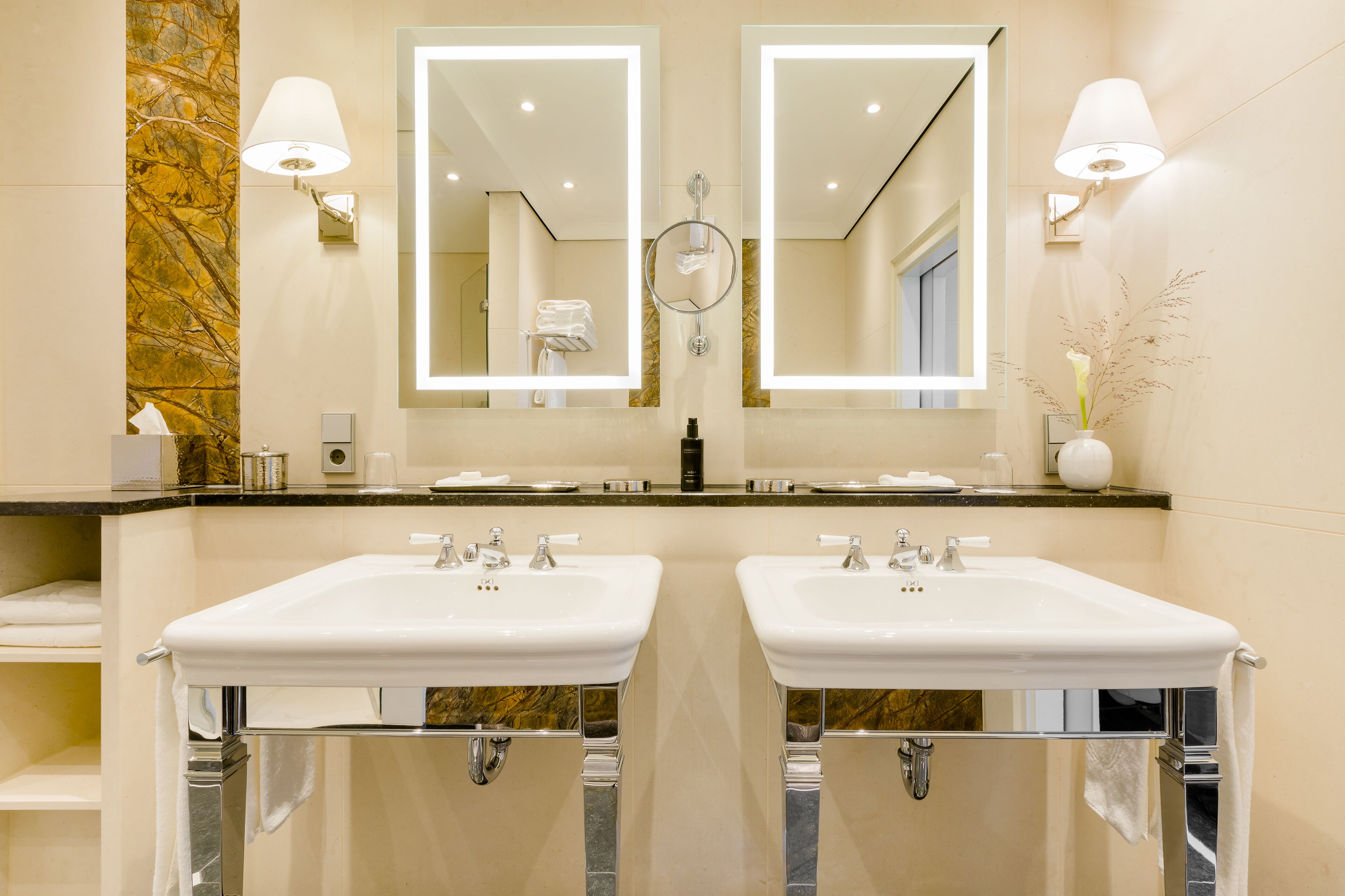 A modern bathroom with two sinks, a large mirror, and a marble accent wall.