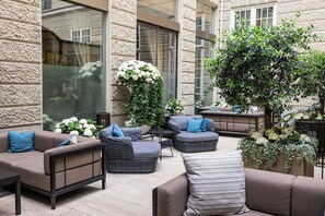 Un espace extérieur aménagé avec des canapés et des fauteuils, une petite table et des plantes en pot.