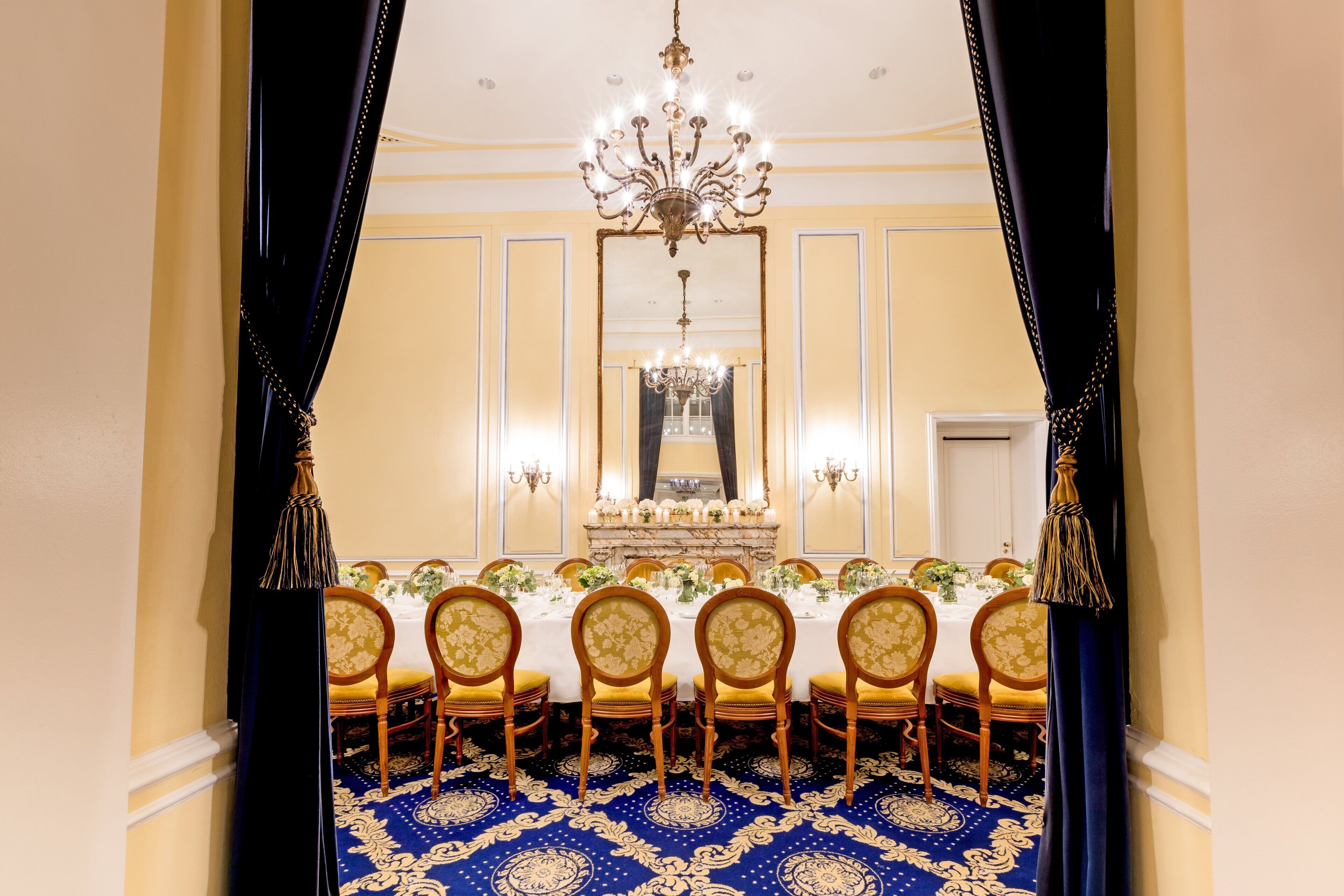 Ein formeller Speisesaal mit einem langen Tisch, gedeckt für eine Mahlzeit, mit Vorhängen und einer Chandelier.