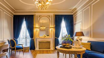 A luxurious room with a fireplace, a chandelier, a blue sofa, and a round table with a lamp.
