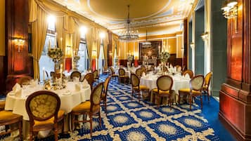 A banquet hall with round tables, chairs, and a blue patterned carpet.