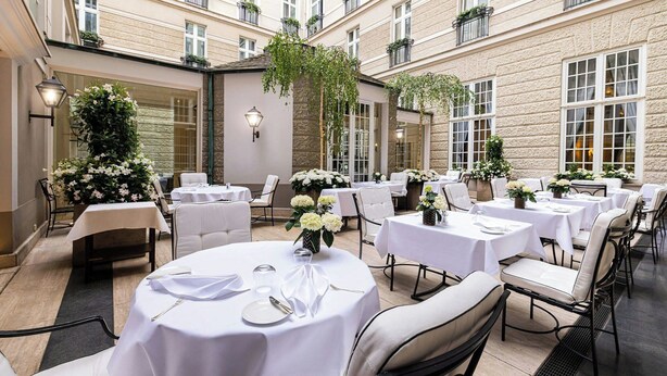 Un patio de hotel con mesas redondas, manteles blancos y sillas.